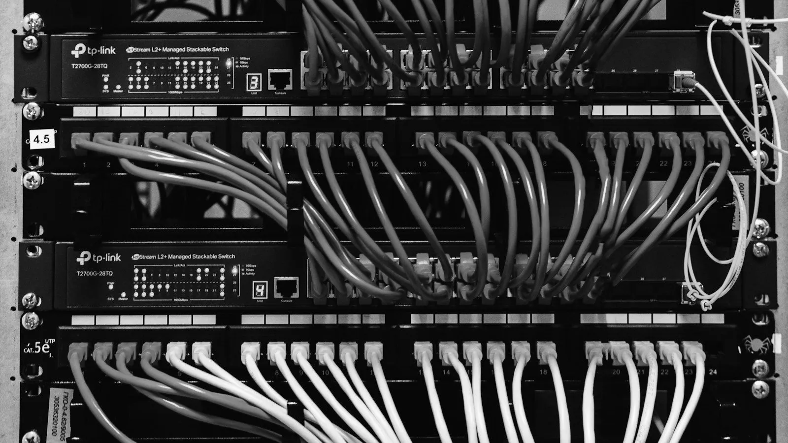 A server rack with patch panels and teal and yellow network cables.