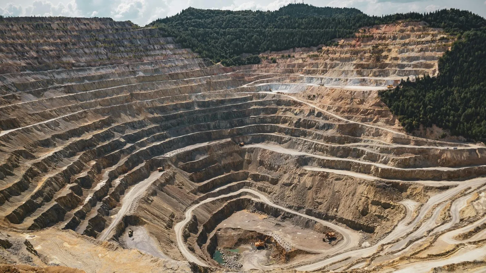 Aerial view of an open-pit mine, its benches stepping down to the pit floor.